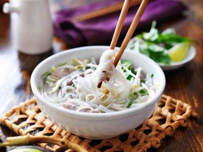 picking up noodles out of a bowl of pho